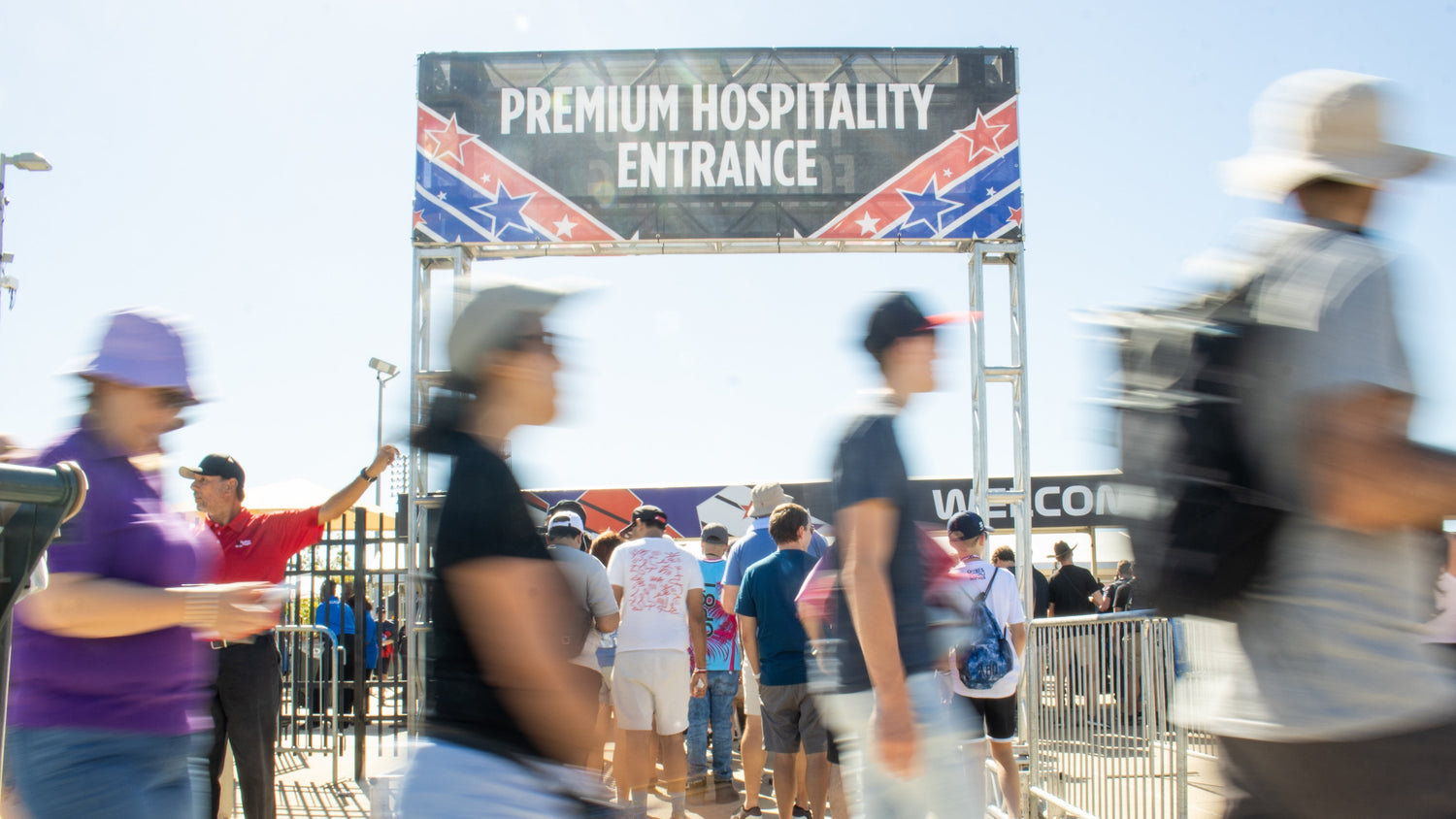 People walking towards a 'Premium Hospitality Entrance' sign with a Confederate flag design.